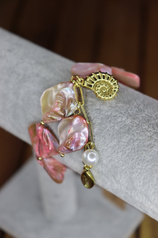 Gold bracelet with pink stones, sea shells and a pearl.