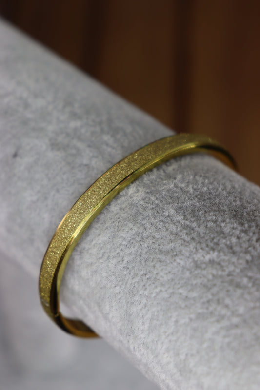 Gold bracelet on a textured white surface