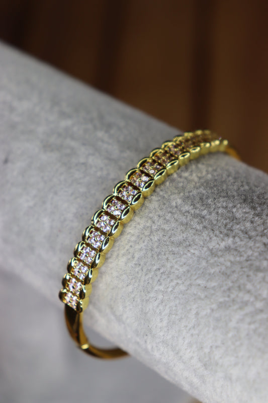 Gold bracelet with diamonds on a gray surface